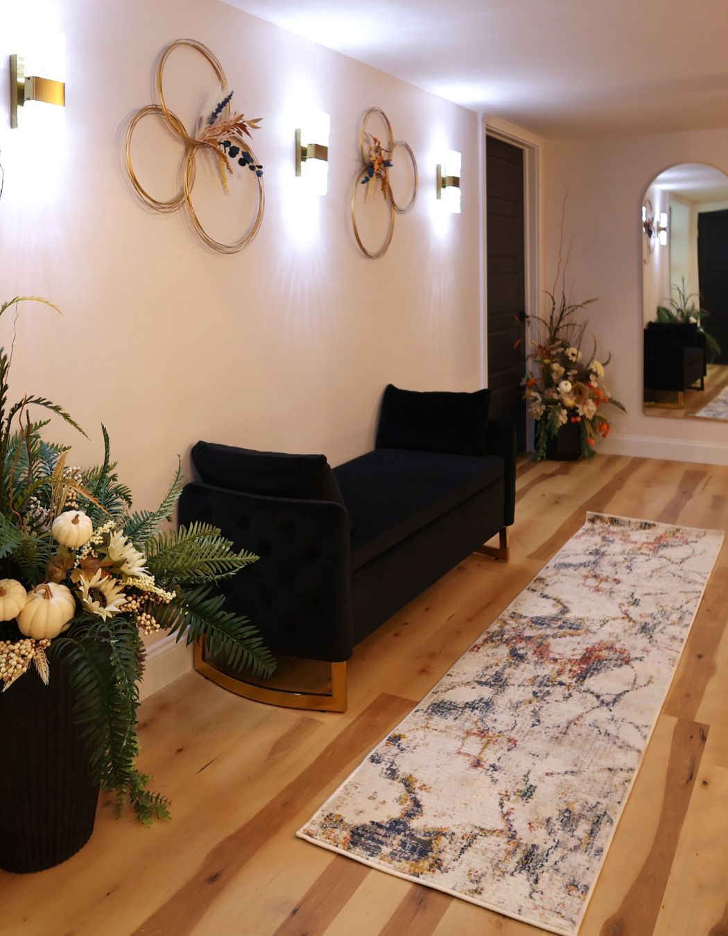 Interior hallway at Elysian Spa at In Vogue in Oswego, New York, featuring a long corridor with soft lighting, a comfortable sofa, a decorative mirror at the end, and doors leading to private treatment rooms.