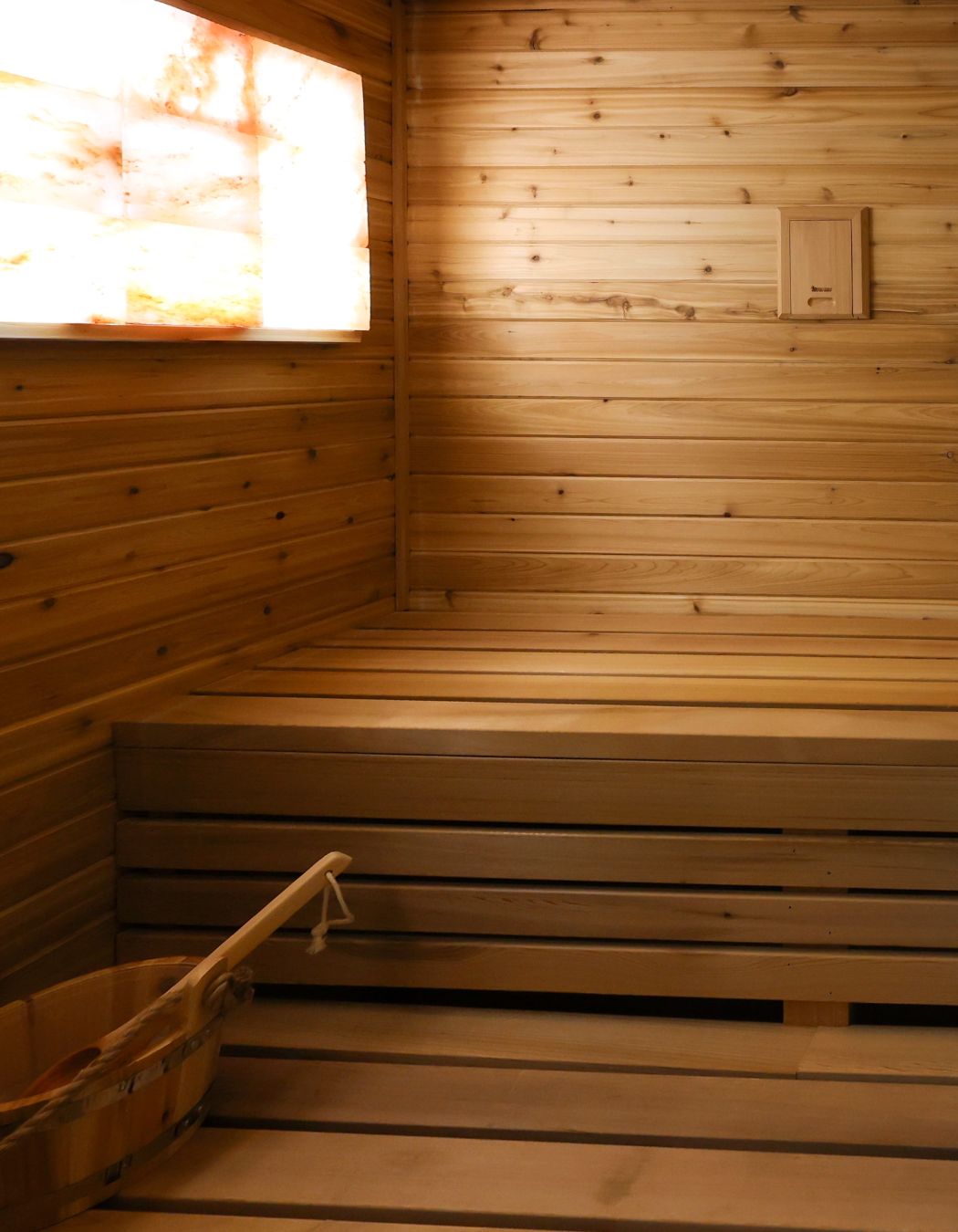 Himalayan salt sauna at Elysian Spa at In Vogue in Oswego, New York, featuring glowing salt walls, warm wood interiors, and a tranquil, therapeutic setting.