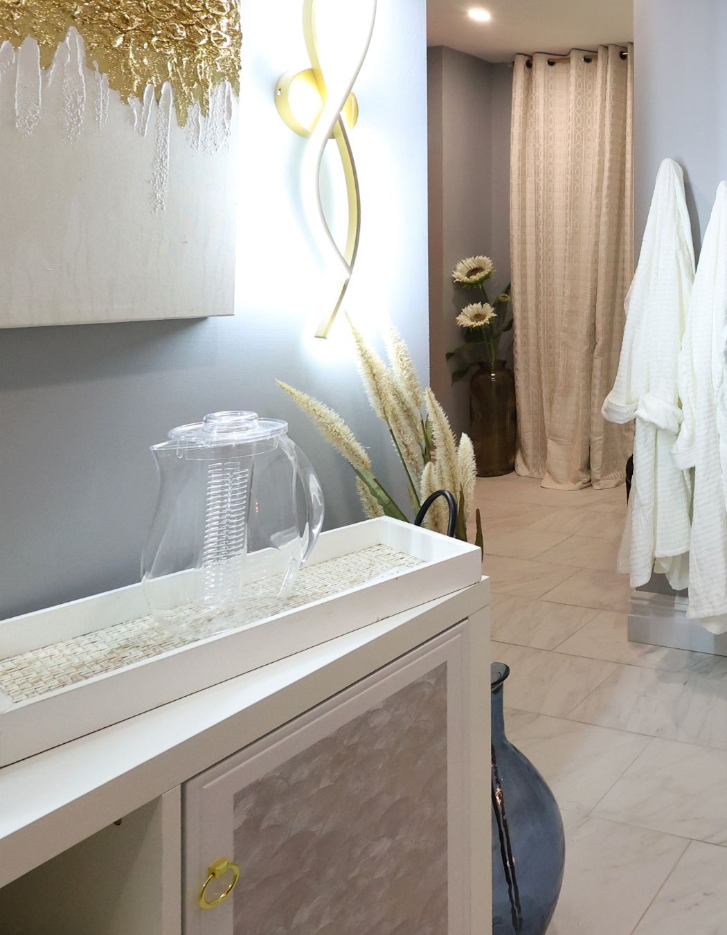 Hydration station and guest robes near the steam room at Elysian Spa in Oswego, New York, offering spa guests water and amenities for relaxation.