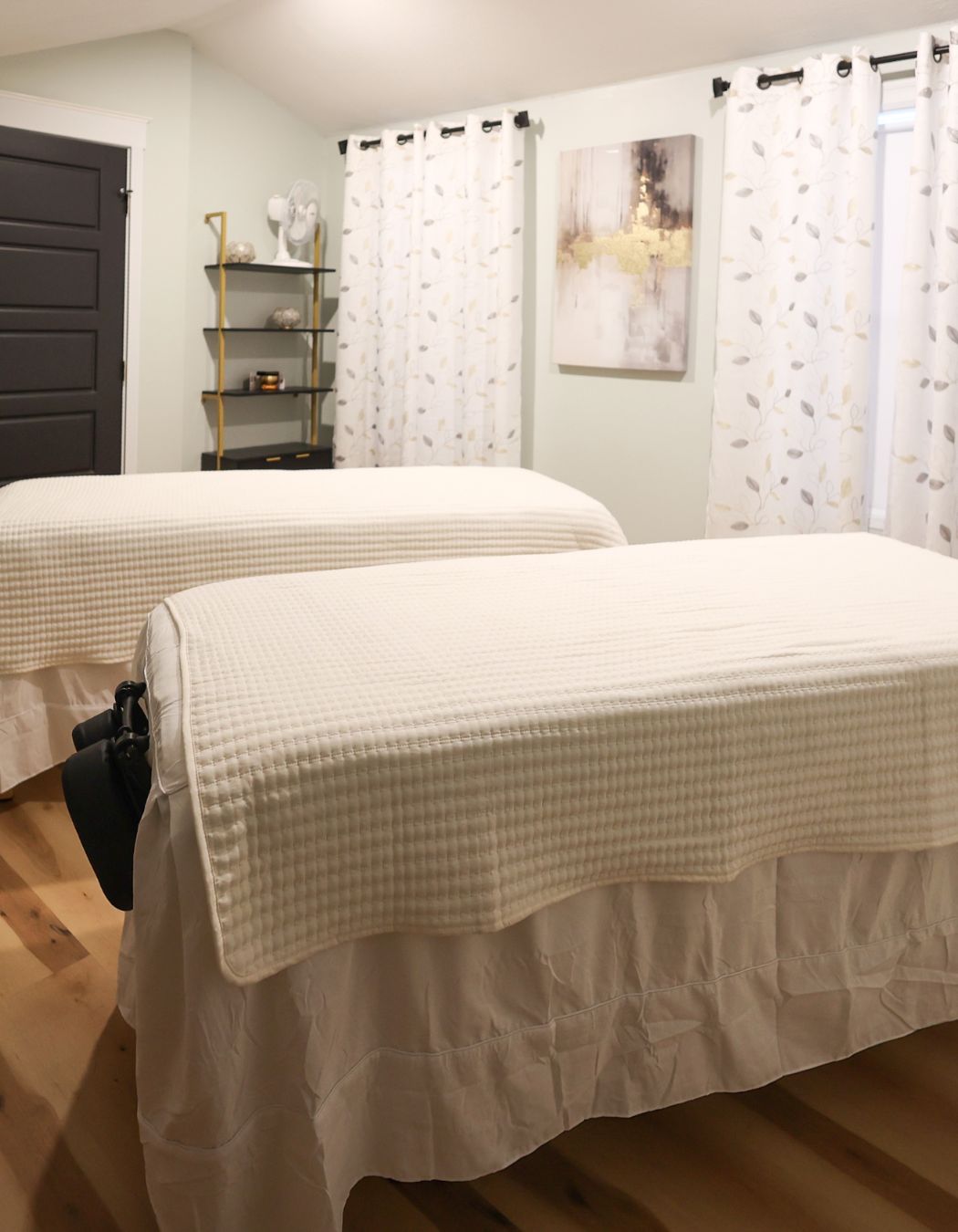 Couples massage room at Elysian Spa at In Vogue in Oswego, New York, showing two spa tables arranged for a relaxing shared experience.